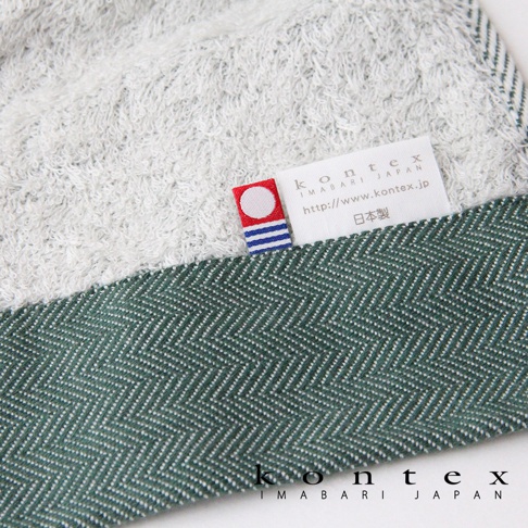 HERRINGBONE 今治長纖有機棉斜紋浴巾，採用綠色斜紋編織，搭配白色毛圈織物，質感細膩，並帶有品牌標籤。