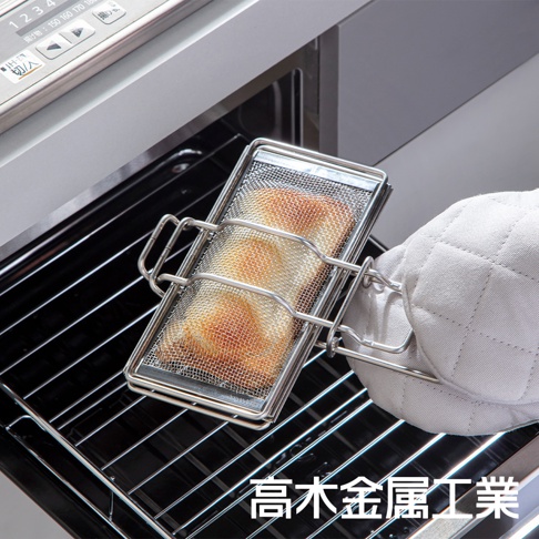 銀色不鏽鋼網製烤箱吐司夾，夾著一片金黃色吐司，由戴著白色隔熱手套的手取出，置於烤箱烤架上。