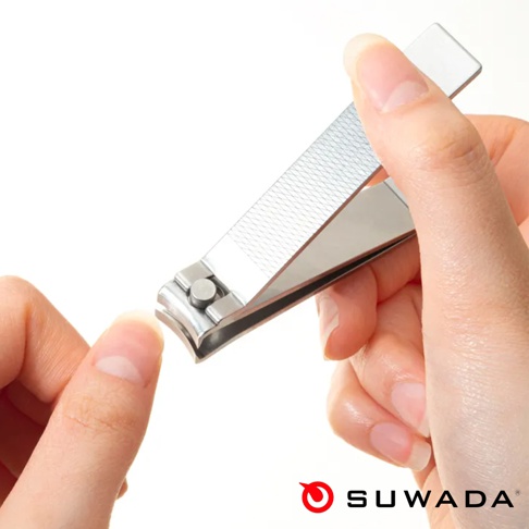 一雙手正在使用金屬質感的 SUWADA 品牌可折疊指甲剪，設計精緻且表面有細密的防滑紋路，動作聚焦在修剪指甲的過程，呈現出簡約、高品質的生活小物特寫。