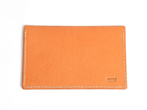 淺橙色皮革製成的存摺文件收納夾，邊緣有白色縫線，右下角壓印有「HERZ」和「MADE IN JAPAN」字樣。