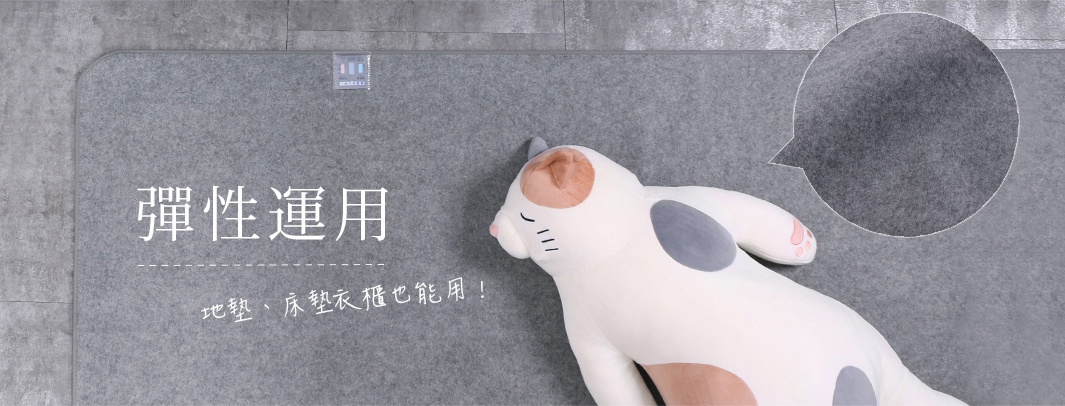 單人備長炭防潮床墊，灰色毛氈材質，表面有細緻紋理，角落圓潤。右側有一填充式貓咪玩偶，白色身體帶有橘色、灰色斑紋。