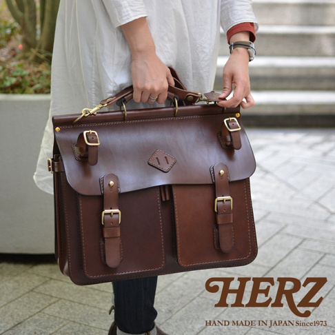 職人手作深棕色皮革旅行包，採用優質皮革製作，設有兩層翻蓋設計，配以多個金屬扣環及前置雙口袋，適合日常或旅行攜帶。