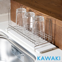 白色珪藻土板上放置著一個銀色金屬網架，架上立著三個透明玻璃杯，杯口朝下，金屬架的支撐架和網格清晰可見，整體置於廚房水槽旁的木質檯面上。