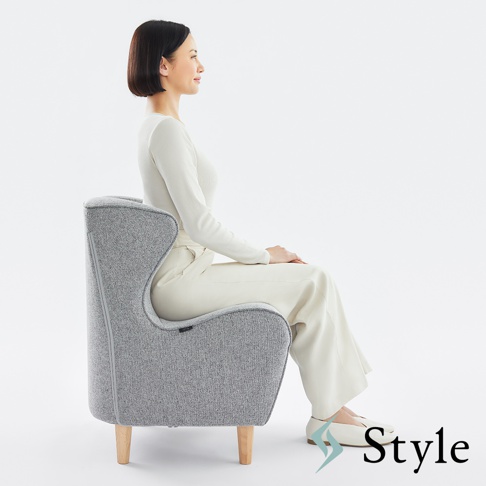 灰色布藝美姿調整座椅，立腰設計，配有四支木質椅腳，一位女士側身坐在座椅上。