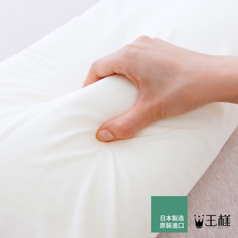 一隻手正在擠壓一個白色天竺棉材質的枕套，展現其柔軟度和彈性。