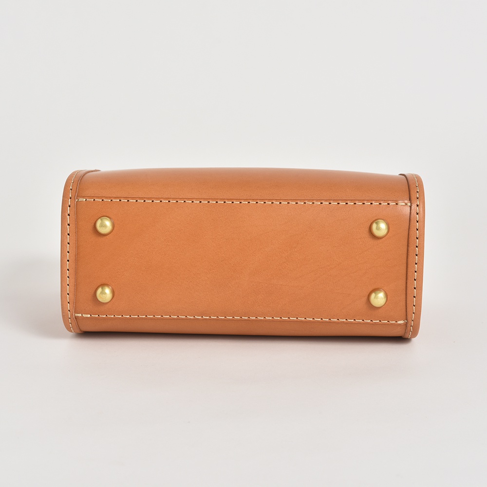 職人手作皮革迷你波士頓包 CW-11，天然棕色皮革，包身底部有四個金色卯釘，搭配米白色車縫線。