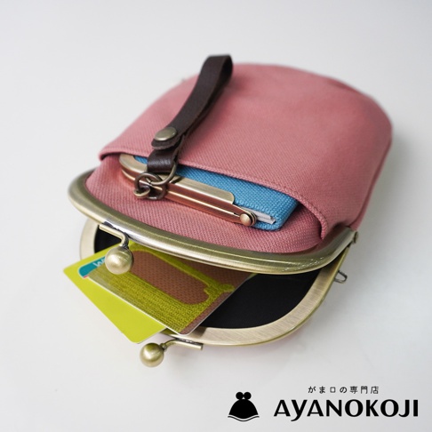 京都職人手作 AYANOKOJI 桃紅色帆布腰掛口金包，內含藍色小內袋，包口有復古金屬扣和皮質提帶，外面露出部分信用卡。