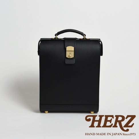 黑色皮革製成的職人手作杜勒斯商務後背包，配有金色金屬鎖扣和提把，底部設有金色腳釘。