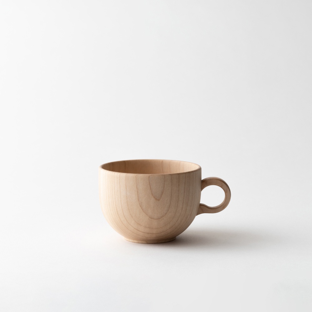 一個淺木色、圓潤的楓木茶杯，帶有彎曲的把手，呈現自然的木紋。