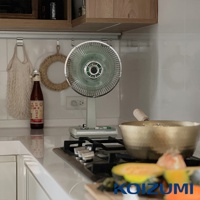 復古風格的白色電風扇，扇葉為綠色，金屬網罩，置於廚房檯面上。