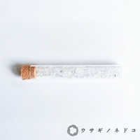 玻璃試管瓶裝有透明的碎裂礦石，瓶口以軟木塞封閉。