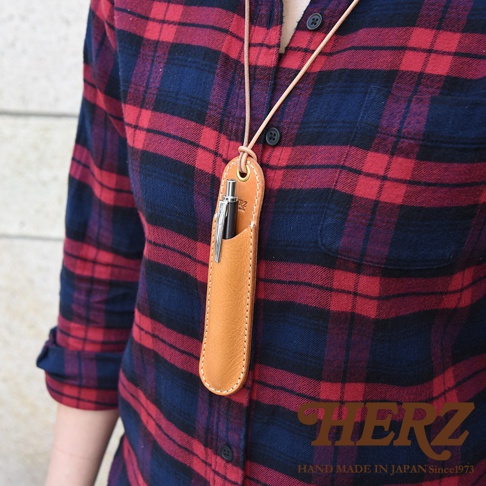 模式B： 一位身穿紅藍格紋襯衫的人，頸部掛著一個淺棕色皮革製的筆套，筆套內插著一支銀色鋼筆。