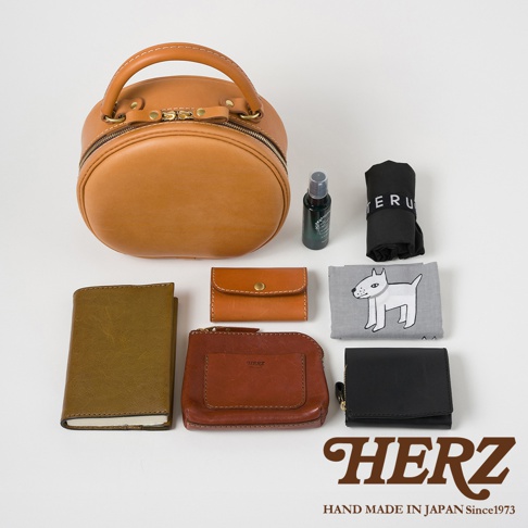 HERZ 職人手作皮革兩用圓形包，搭配皮夾、筆記本、小瓶噴霧及印有狗狗圖案的布巾，展現日式手作質感。