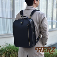 黑色職人手作皮革兩用後背包，配有金色拉鍊和搭扣，展現簡約俐落的商務休閒風格。