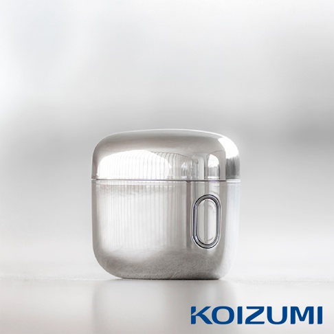 銀色金屬質感的小型KOIZUMI超迷你刮鬍刀，外型簡約圓潤如耳機盒，機身側面設有橢圓形按鈕，整體呈現平滑的鏡面反射效果，置於乾淨明亮的純白背景中。