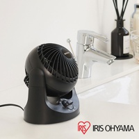 黑色桌上型空氣循環扇，具有可調整角度的球狀扇頭，底部有黑色旋鈕控制風速。產品擺放在白色檯面上，背景是鉻合金水龍頭和黑色擴香瓶。