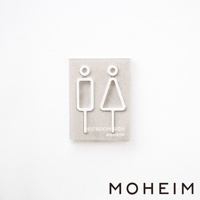 一對白色簡約風格的男女廁所標示牌，由木頭製成，呈現簡潔的幾何線條，分別代表男性（長方形）和女性（三角形）的抽象圖形，置於淺色背景上。