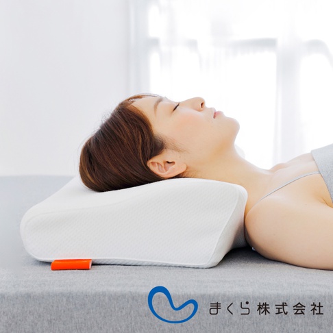 白色護頸止鼾枕，採用蜂巢狀織紋布料，枕頭中央低陷，兩側略高，符合人體工學設計，枕頭一角有橘色小標籤。