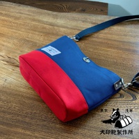 犬印純綿帆布雙色迷你側背包，採用海軍藍與紅色拼接設計，帆布材質，配有可調節式肩帶，整體風格簡約。