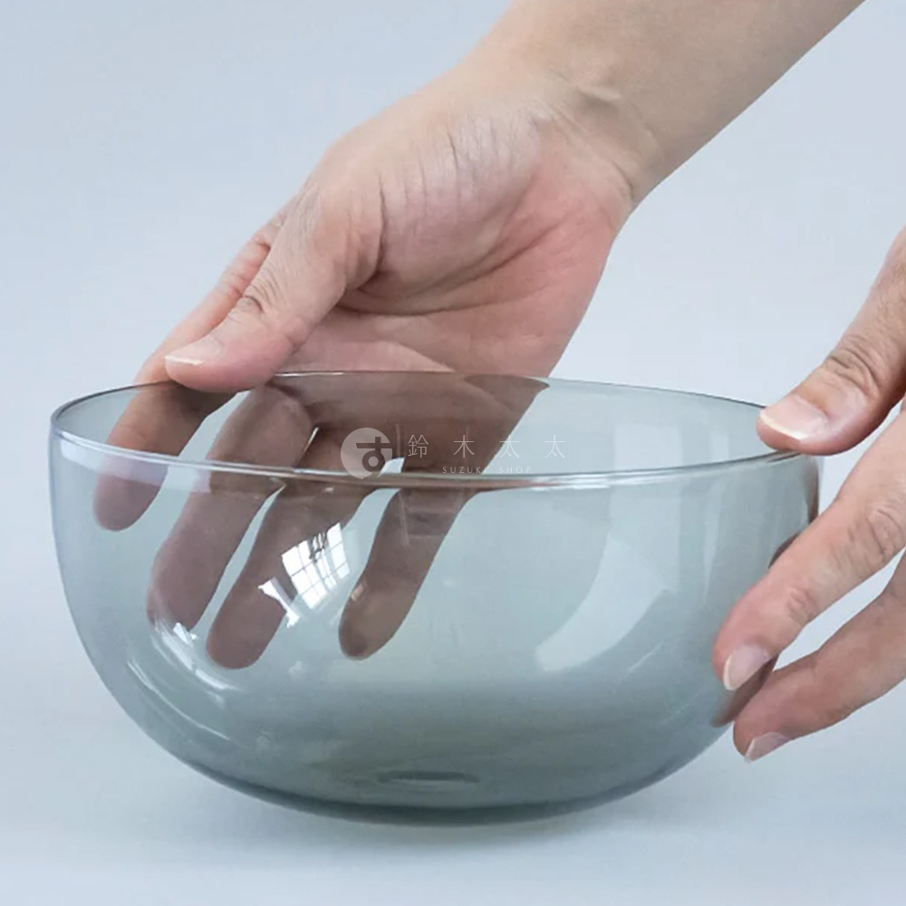 雙手捧著一個圓潤的玻璃點心碗，碗呈半透明的灰藍色，碗壁光滑，邊緣圓潤。