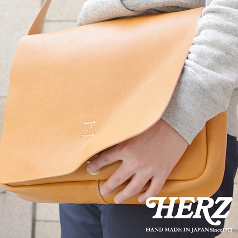 日本 HERZ 職人手作軟皮橫式斜背包，以淺棕色皮革製成，包面上繡有白色字母 Z，下方有金色旋釦，包身縫線細緻，整體散發職人手作質感。
