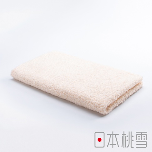 一條淺米色、觸感細緻的今治毛巾，折疊置於白色背景上。毛巾表面呈現柔軟蓬鬆的絨毛感，材質應為棉。