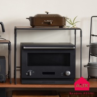 工業風單層置物架，黑色金屬支架搭配木紋層板，上方擺放一個棕色BRUNO多功能烹調鍋，下方是一個黑色嵌入式電烤箱，旁邊還有灰色鍋具堆疊的置物架。