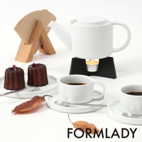 白色陶瓷茶壺，搭配黑色加熱座上的茶蠟，旁邊有兩個法式費南雪蛋糕、咖啡杯和濾紙架。