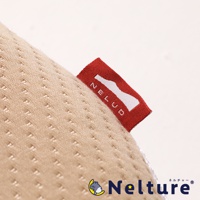 淺米色織物材質的枕頭，表面有細小的壓紋，右側縫有一個紅色標籤，上面印有白色「NELUD」字樣和一個輪廓圖案。