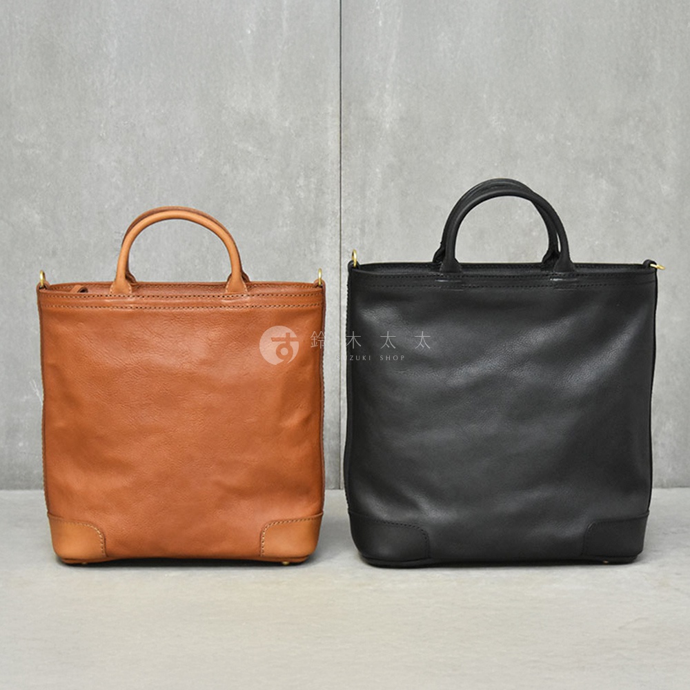 日本HERZ職人手作皮革Organ兩用拉鍊托特包，分別為焦糖色及黑色，兩款包皆呈現垂直方正的廓形，上方配有提把，並設有可拆卸的長背帶。