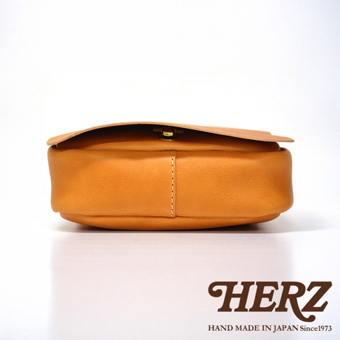 HERZ 職人手作皮革軟皮直式斜背包，從側邊拍攝，展現其製作精緻的皮革質感與圓潤的包身線條。