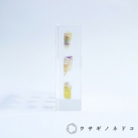 透明壓克力塊中垂直排列著三塊帶有黃色、紫色和粉色色塊的螢石切片標本。