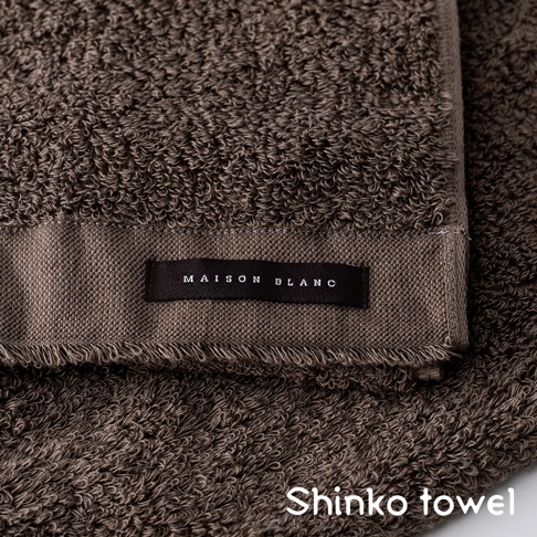 MAISON BLANC 淺棕色柔膚匹馬棉浴巾，特寫浴巾織紋與品牌標籤。
