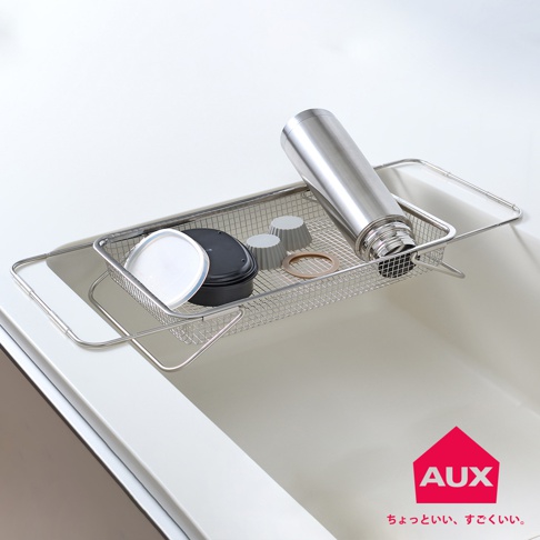 不鏽鋼伸縮瀝水籃，籃內有保溫瓶、黑色餐盒、白色盒蓋、兩個灰色矽膠杯及一個橡皮圈，置於白色水槽上方。