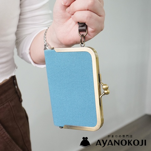 AYANOKOJI 品牌藍色帆布橫式口金卡片收納包，以掛繩懸掛，特寫包包細節。