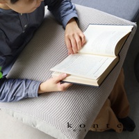 米白色針織紋理萬用彈性枕套，蓋在淺灰色枕頭上，一人正手持一本打開的書閱讀。