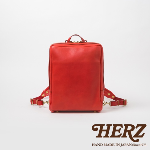 紅色皮革製成的方形商務後背包，附有可調節的肩帶和頂部提把，皮革表面光滑。