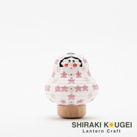 白色紙質達摩不倒翁提燈，帶有粉色櫻花圖案和金色點綴，臉部繪有傳統日式風格的五官，立於圓形木質底座上。