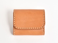 職人手作皮革雙折收納零錢包，採用天然棕色皮革製成，外觀簡約，邊緣有手工縫線裝飾，整體呈現質感。