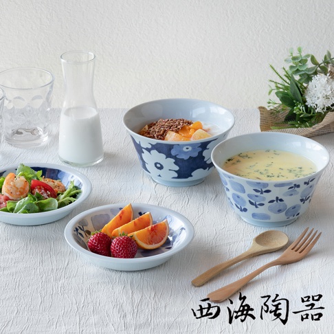 波佐見燒藍花紋四件式丼飯碗盤組，包含兩個大小不同的藍花紋陶瓷碗，一個裝有麥片水果，另一個裝有濃湯。另有兩個小盤，分別裝有沙拉和水果，以及一組木質湯匙叉子。