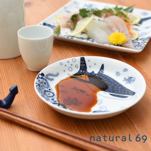 白色陶瓷小碟，繪有藍色線條描繪的魟魚、小魚和氣泡圖案，碟中盛有醬油。