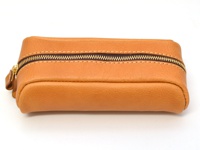 職人手作皮革圓角收納筆袋，呈現溫潤的焦糖棕色，採用真皮材質，搭配深棕色縫線與黃銅色拉鍊，整體簡潔實用。