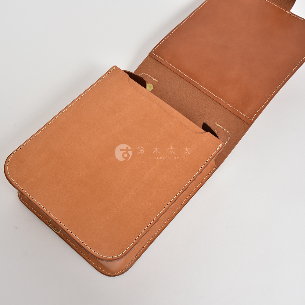 職人手作皮革立體口袋兩用單肩包，以棕褐色皮革製成，車線整齊，包蓋翻開，露出內部隔層。