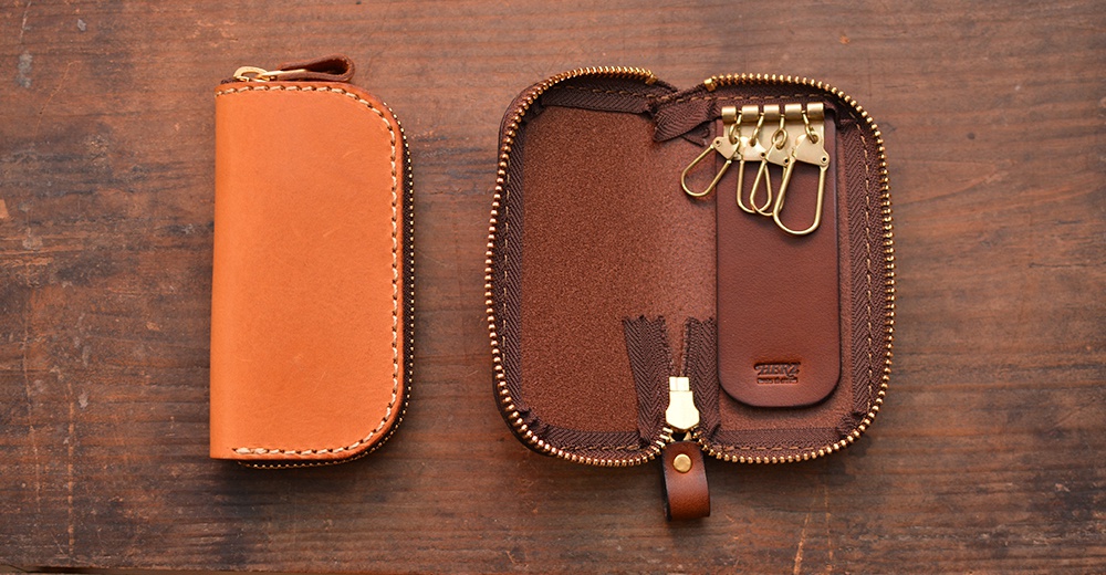 一個棕褐色皮革鑰匙包，閉合狀態和打開狀態，展示了裡面的四個金屬掛鉤。