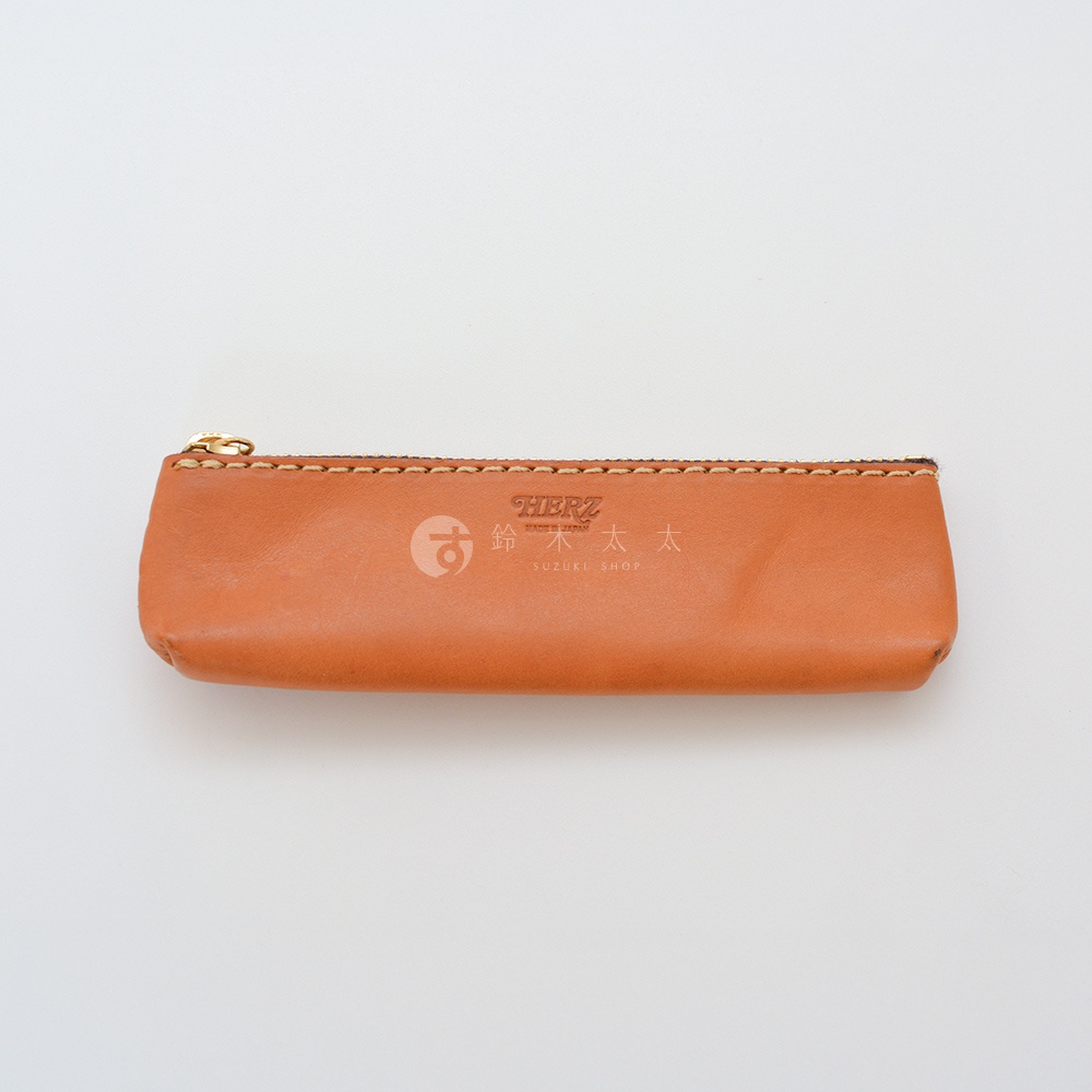 職人手作皮革經典收納筆袋，淺棕色，帶有金色拉鍊和縫線細節，表面壓印有品牌標誌。