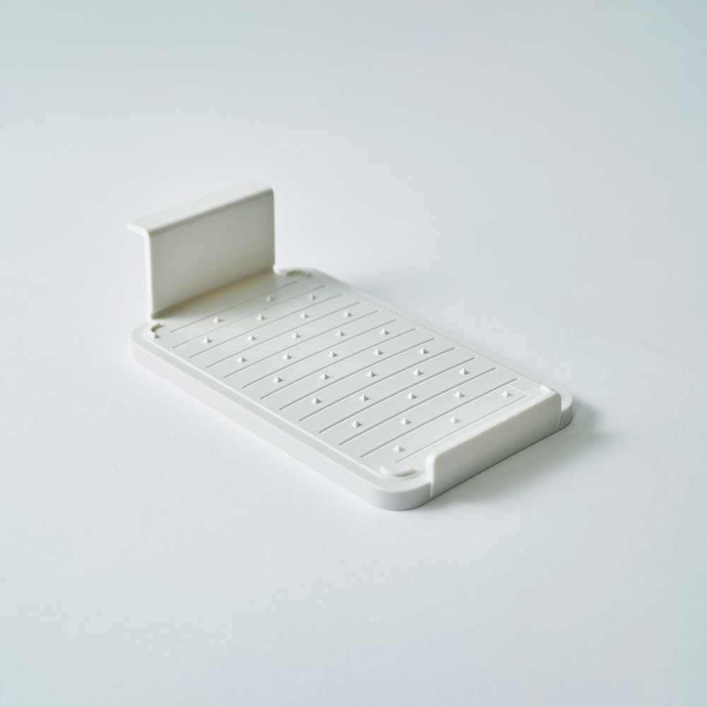 一個白色塑膠奶油盒，表面有細長的排水溝槽和多個突起的圓點，一側有 L 形支架。