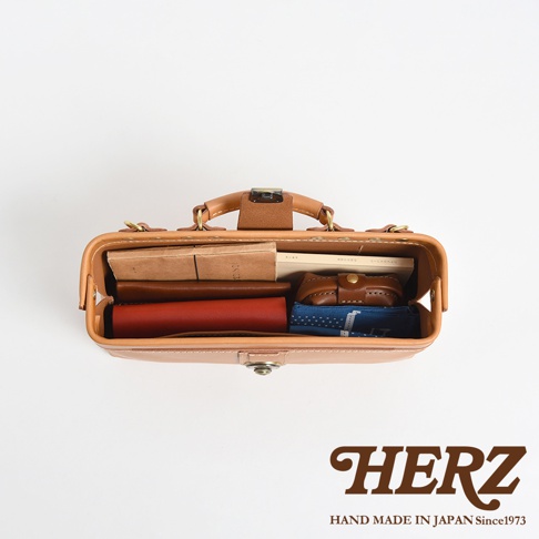 日本HERZ品牌皮革側背包，內部裝有書籍、皮夾和藍色圖案的物品