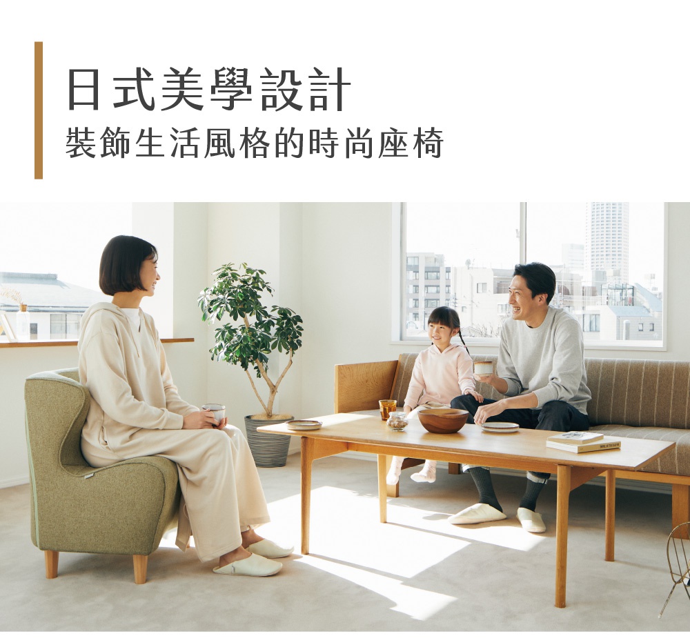 綠色布藝椅，椅背較高，帶有扶手，椅腳為木質。旁有一株綠葉盆栽，以及一張木質桌子，桌上有碗、盤和書籍。