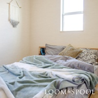 抗菌短絨雙人毯，呈現柔和的淺綠色漸層與白色，材質觸感舒柔。毯子鋪陳在雙人床上，搭配灰色與幾何圖案的枕頭。