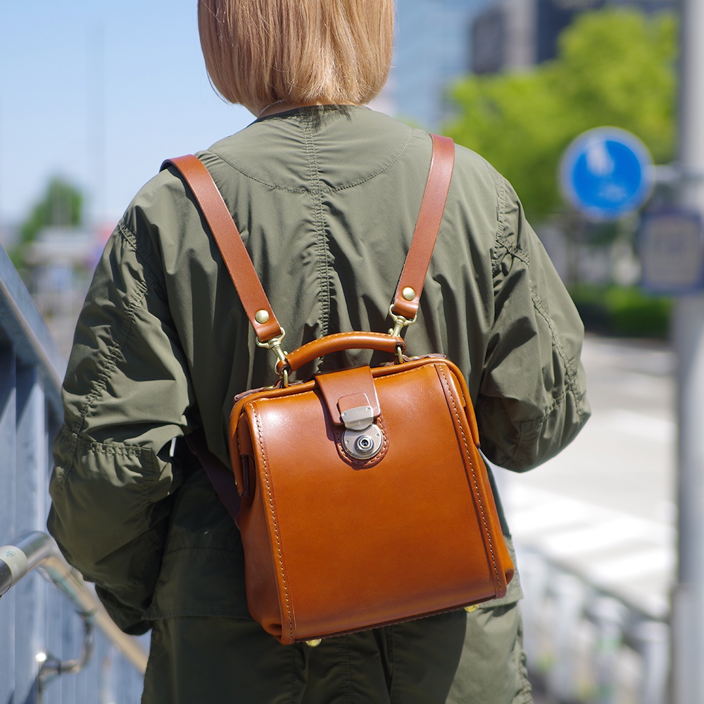 職人手作皮革迷你後背醫生包，採用經典棕色皮革，搭配銀色金屬鎖扣及銅色扣環，設計簡約有型。